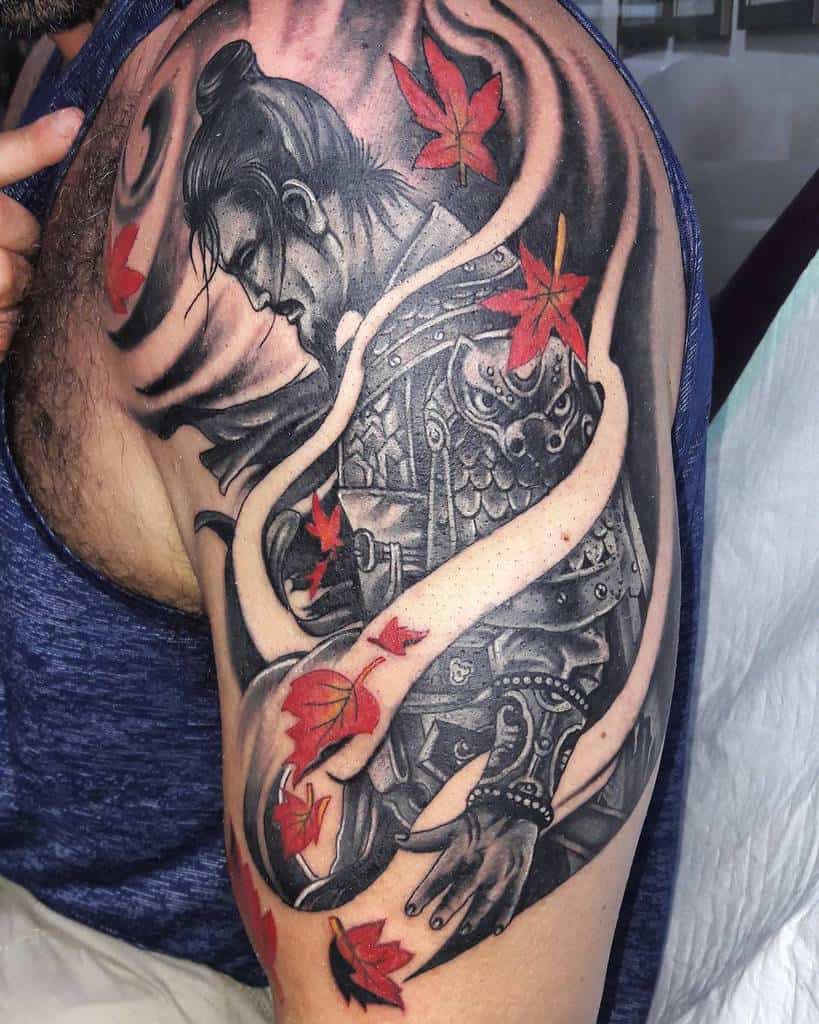 Beautiful upper arm tattoo of a Ronin in intricate armor, surrounded by flowing ribbons and vibrant red maple leaves for a dynamic effect