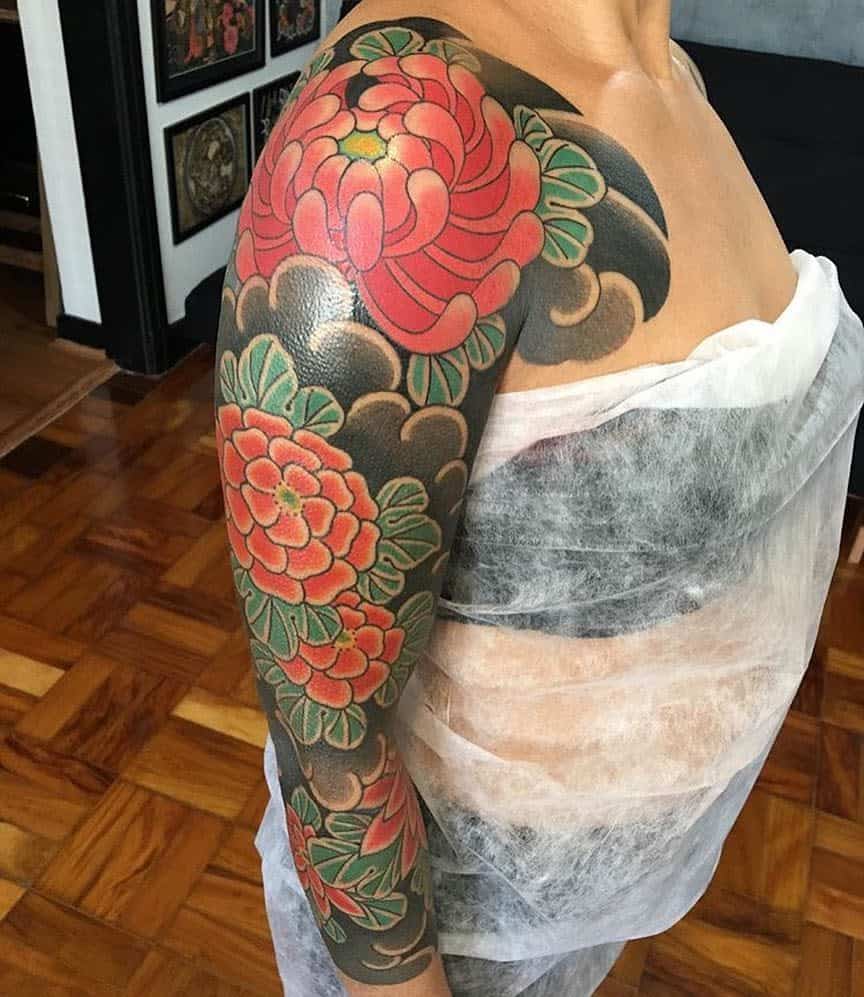 Full sleeve Japanese-style tattoo with red flowers and dark swirling background