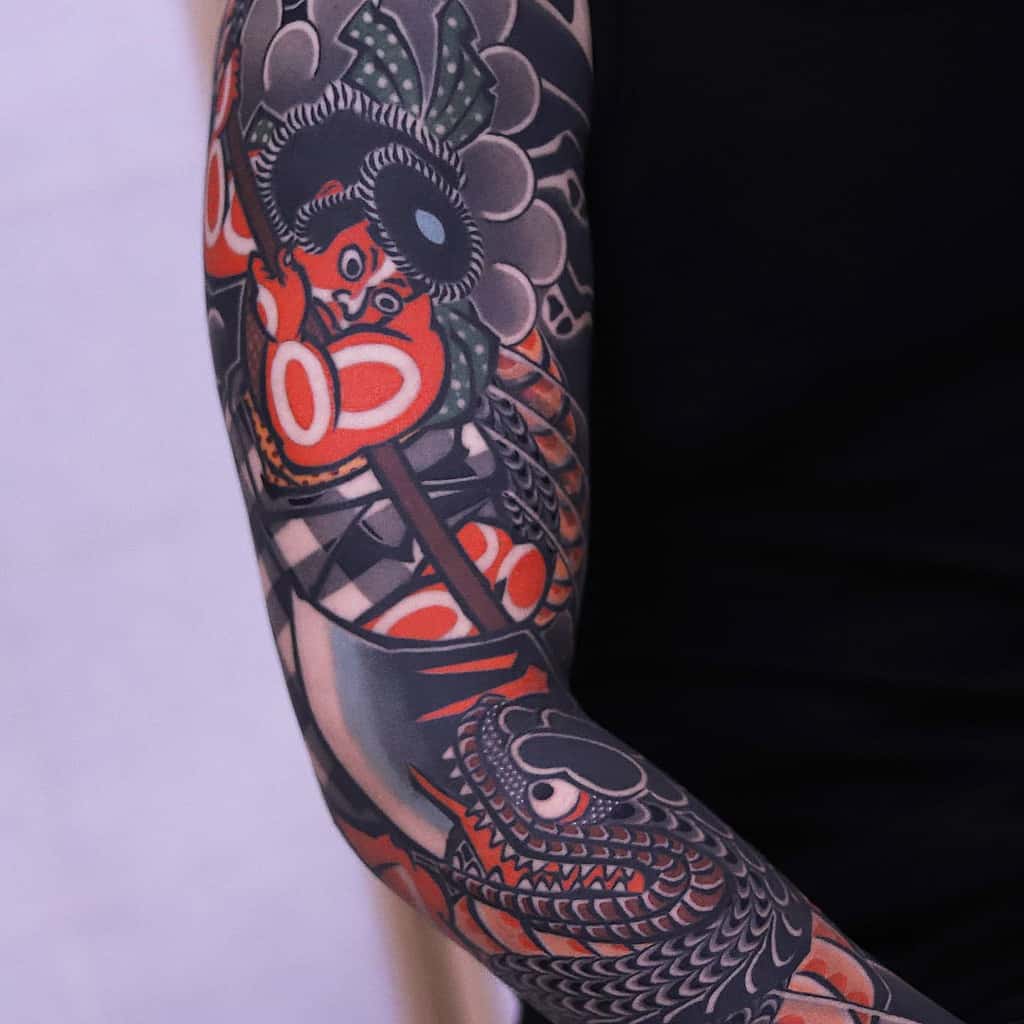 A vibrant Japanese-style sleeve tattoo featuring bold red, black, and grey colors, with traditional elements such as a warrior figure and koi fish wrapping around the arm