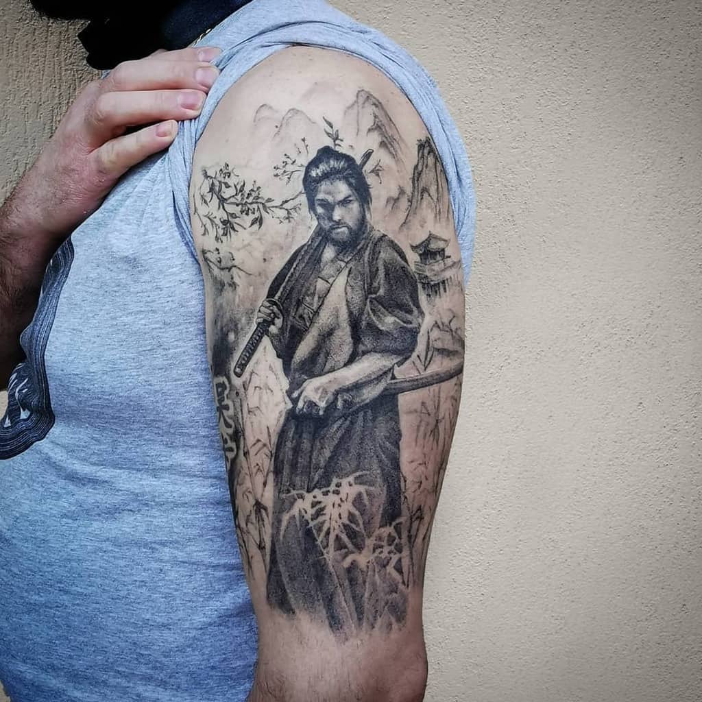 Tattoo of a samurai warrior with mountains and a temple in the background on a man's arm