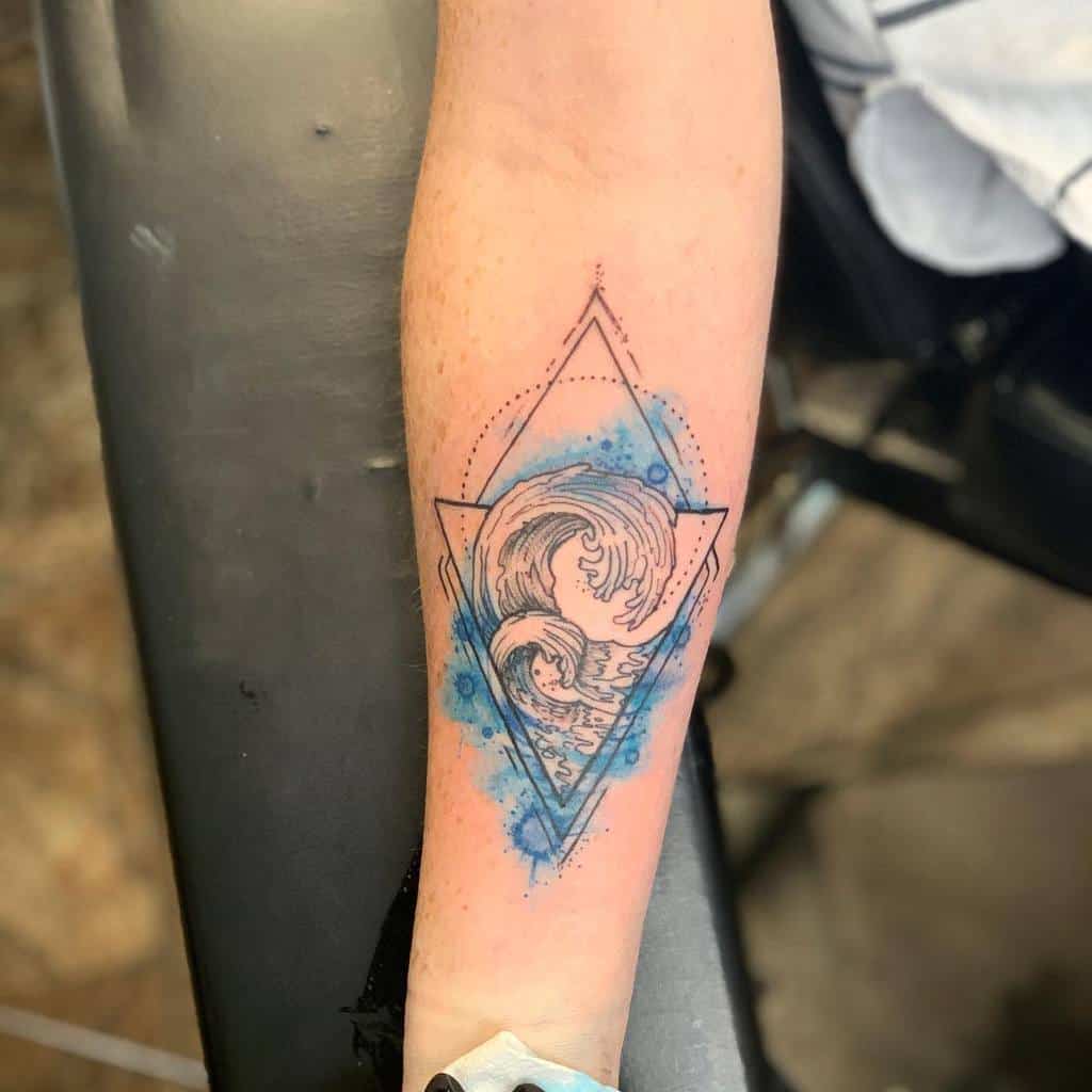 Forearm tattoo with geometric waves inside a diamond frame, accented by watercolor-style blue splashes for a dynamic, modern look.