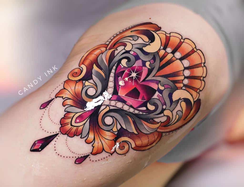Colorful tattoo featuring an ornate gemstone heart surrounded by intricate baroque-style swirls, pearls, gold filigree, chandelier elements, and teardrop jewel accents