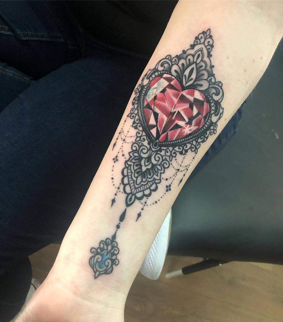 Elegant tattoo featuring a faceted gemstone heart encased in ornate filigree, with chandelier-style beadwork and intricate decorative accents