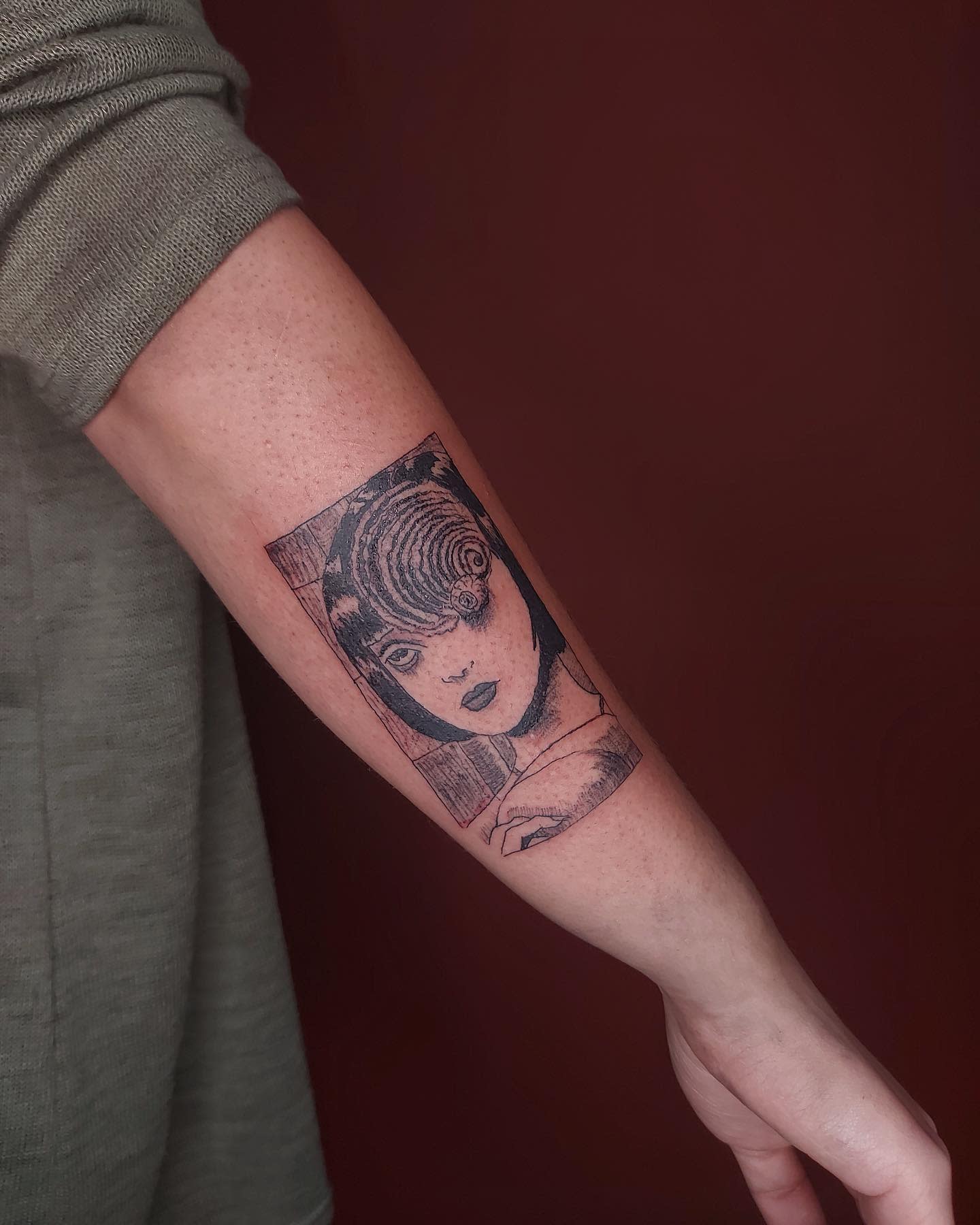 Forearm tattoo of Junji Ito's character with a spiral engulfing her eye, symbolizing madness