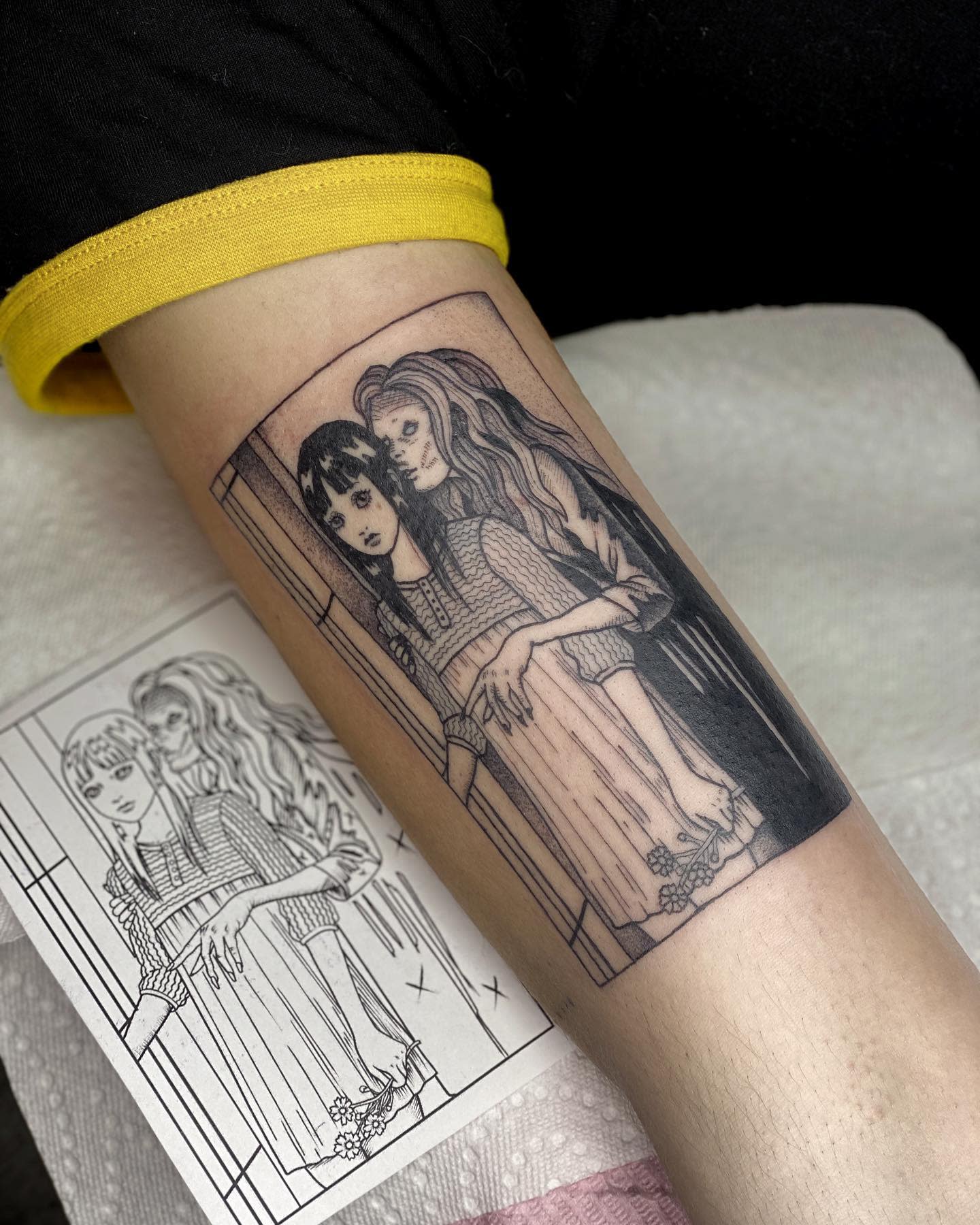 Forearm tattoo of Junji Ito's eerie illustration, showing a girl embraced by a ghostly figure
