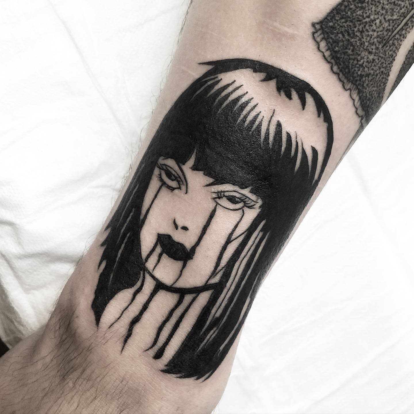 Forearm tattoo of Junji Ito's character with black tears streaming down her face, evoking horror