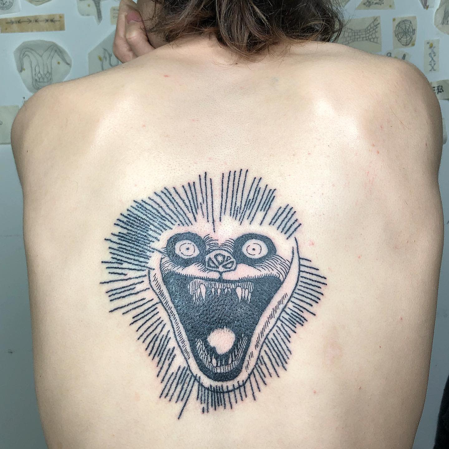 Back tattoo featuring a terrifying wide-mouthed cat with radiating lines, inspired by Junji Ito