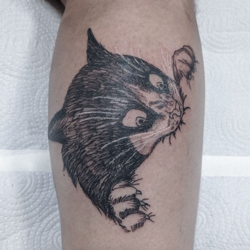 Leg tattoo of a cat with a startled expression and extended claws, inspired by Junji Ito's horror art