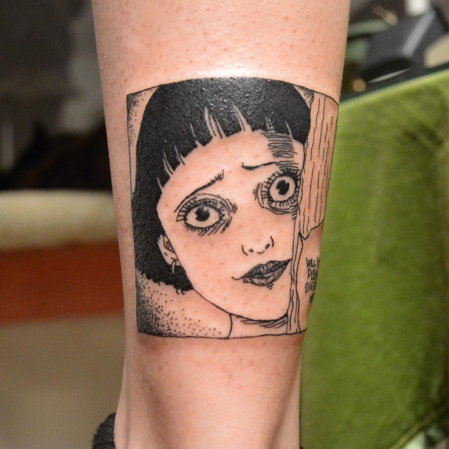 Leg tattoo of a worried-looking Junji Ito character with large, haunting eyes, peeking around a corner