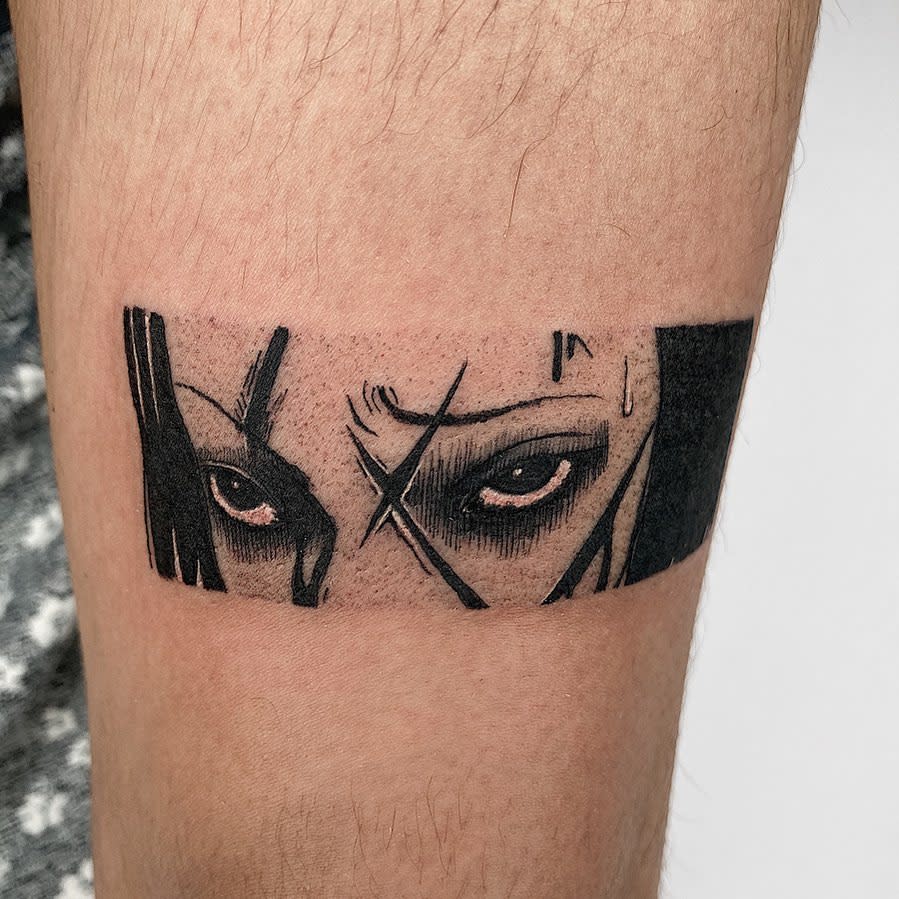 Small forearm tattoo of intense, glaring eyes from a Junji Ito character, conveying a sense of dread