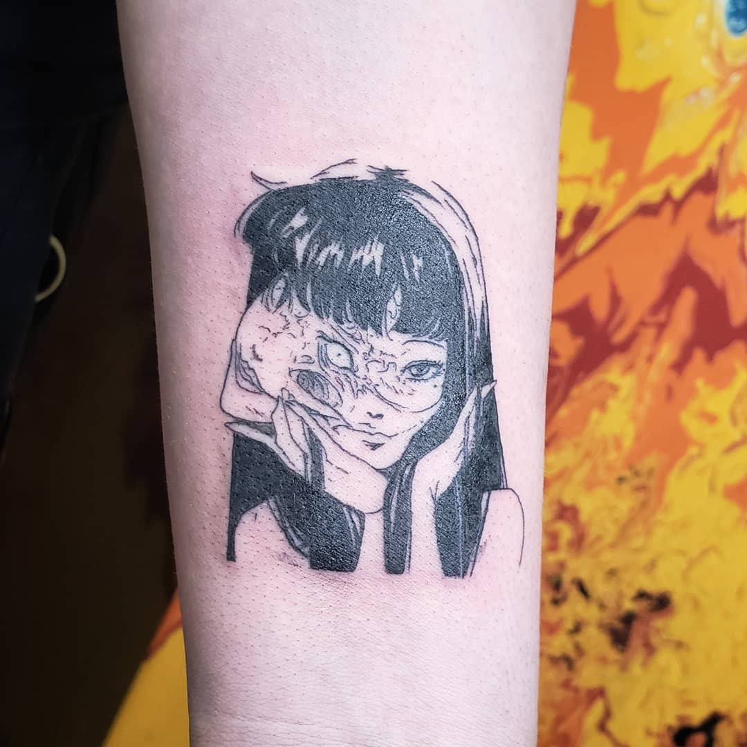 Forearm tattoo of a Junji Ito character with a distorted, melting face, reflecting the horror genre