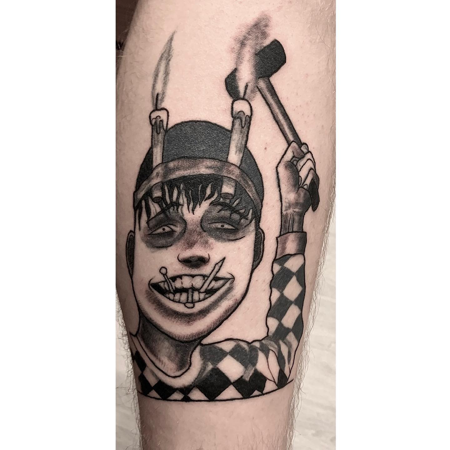 Upper arm tattoo of Souichi from Junji Ito, holding a hammer and nails in his mouth, showcasing his eerie, mischievous grin
