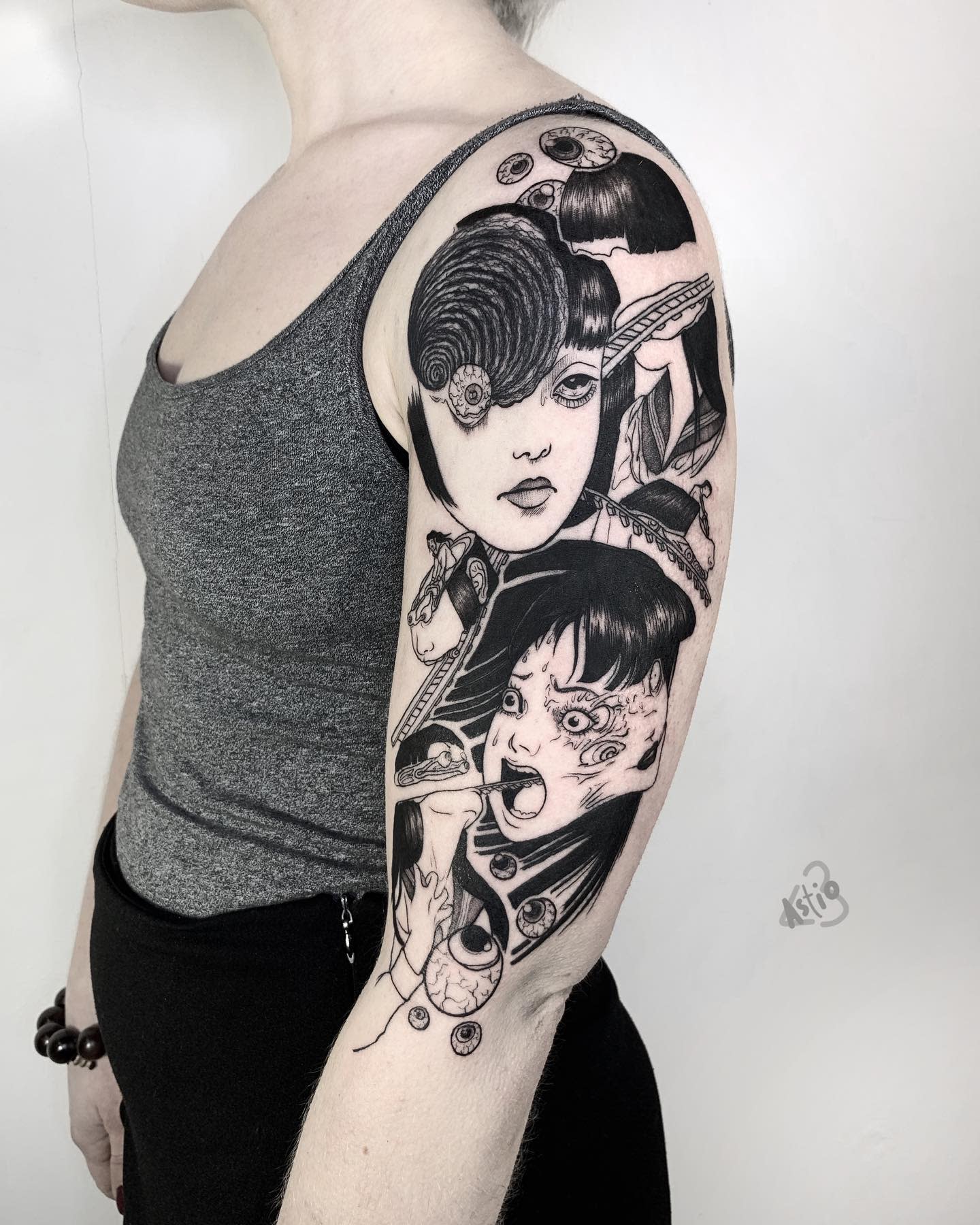 Full sleeve tattoo inspired by Junji Ito's 'Uzumaki,' featuring iconic scenes of spirals, distorted faces, and horror elements cascading down the arm