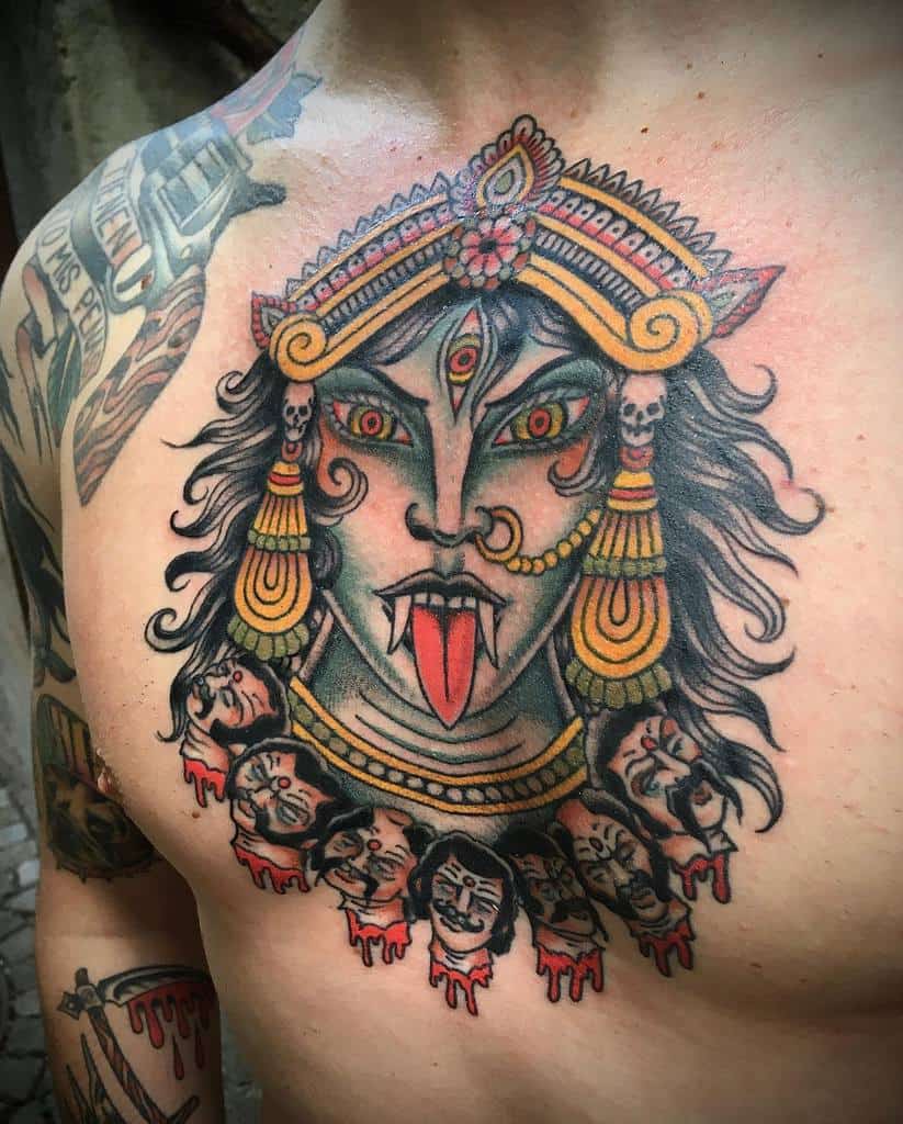 Colorful tattoo of Kali with a third eye, sticking out her tongue, and adorned with heads dripping blood around her neck