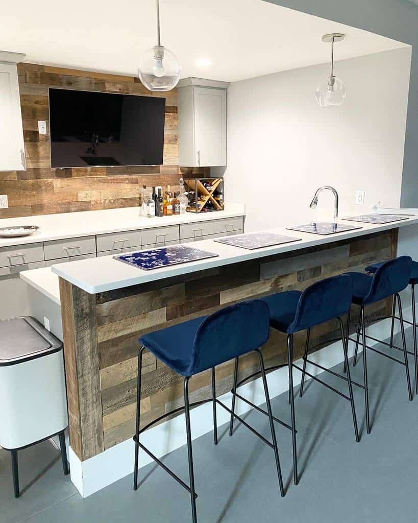 Small kitchen basement bar with reclaimed wood accents, navy bar stools, and pendant lighting.
