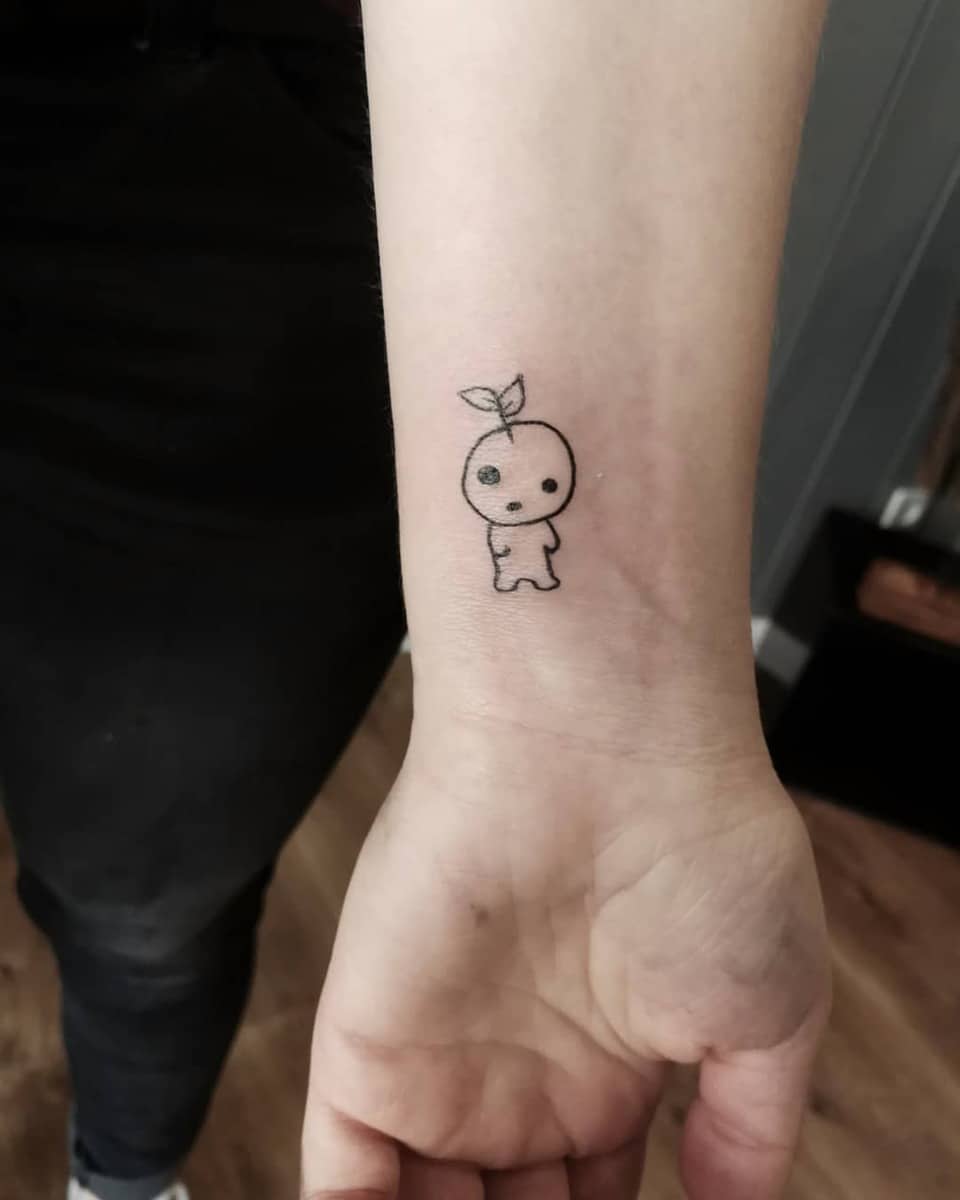 Minimalist tattoo of a single Kodama spirit with a sprout on its head from Princess Mononoke on the wrist