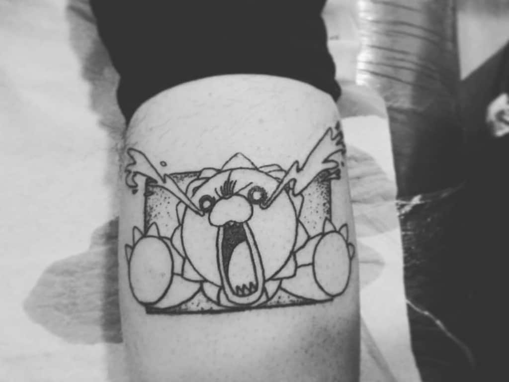Black ink tattoo of Kon from Bleach, featuring his signature plush lion form bursting out of a manga panel with an exaggerated screaming and crying expression