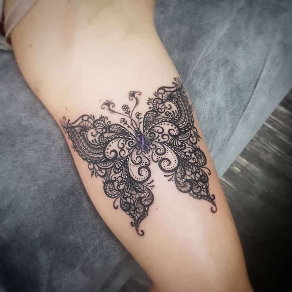 Elegant black lace butterfly tattoo on the thigh, featuring intricate swirls, delicate filigree, and fine ornamental details for a feminine look.