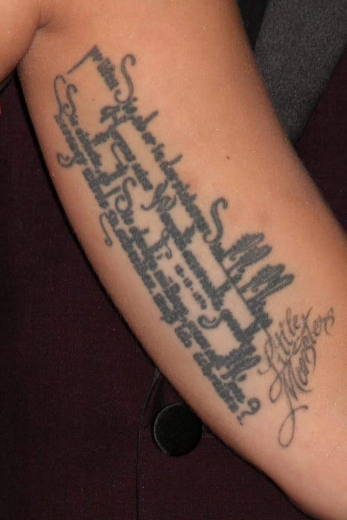 Lady Gaga's black ink tattoo featuring a Rainer Maria Rilke quote in cursive script, including the words 'Little Monsters' in elegant lettering