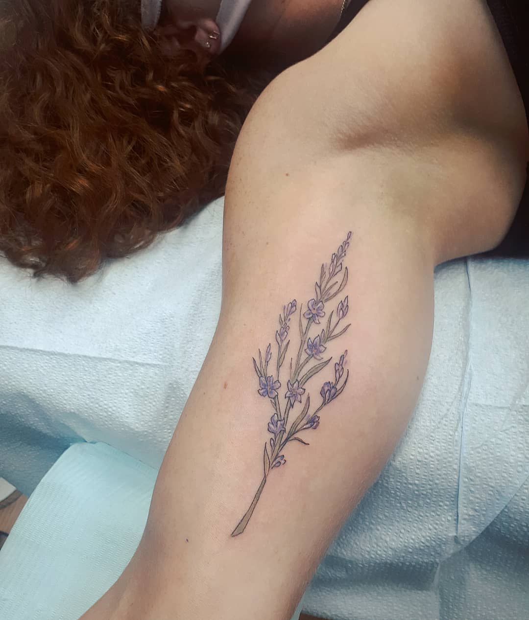 Close-up of a larkspur flower tattoo on an inner arm