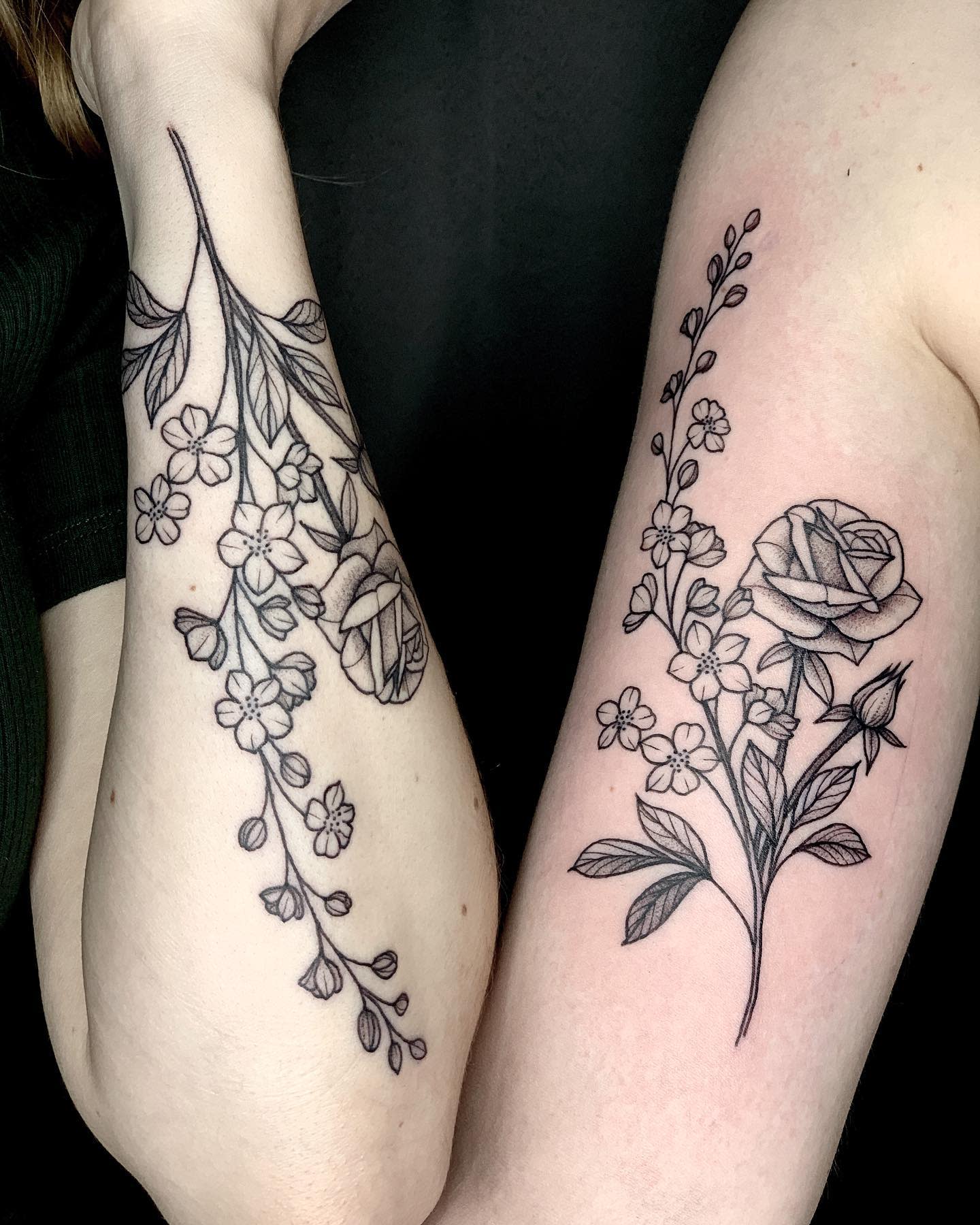 Floral tattoo with roses, larkspur, and leaves on an arm