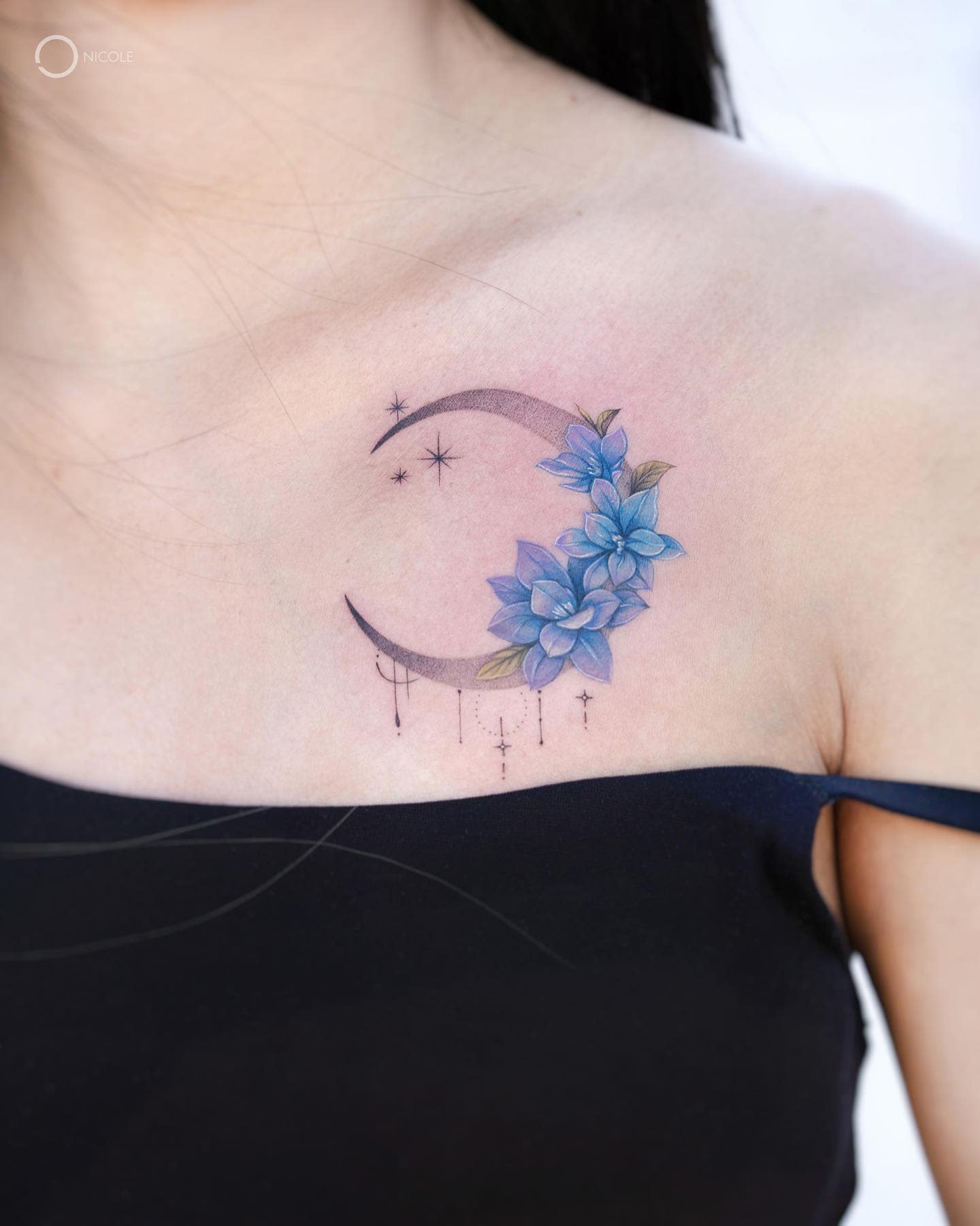 Tattoo of a crescent moon with blue flowers and stars on an upper chest