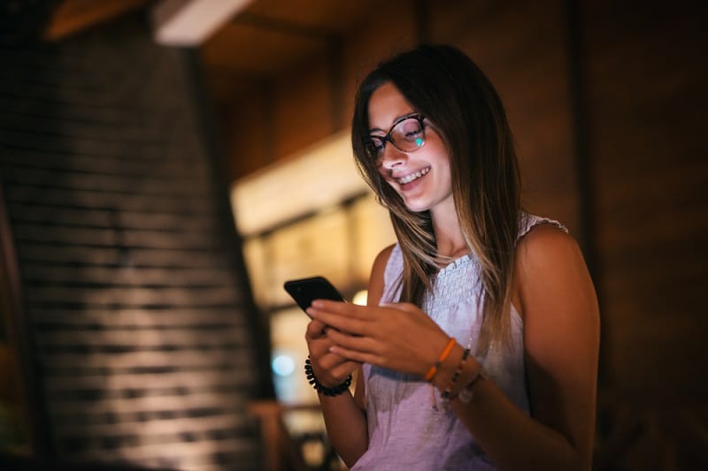 Laughing Woman Looking At Phone At Night