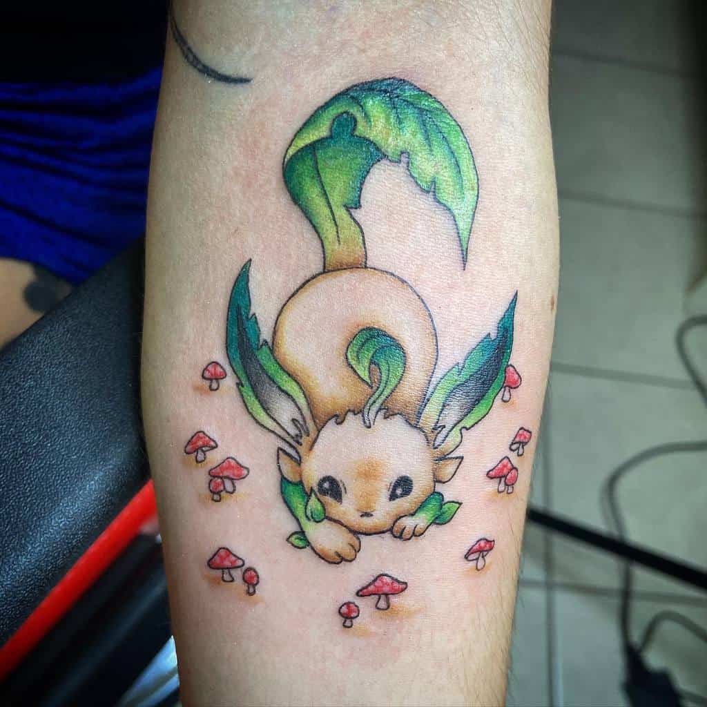 Whimsical Leafeon tattoo with vibrant green leaf accents, surrounded by tiny red mushrooms for a forest-like theme
