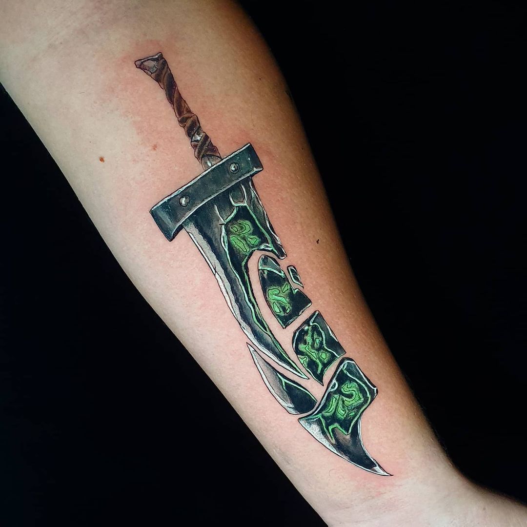 Colorful tattoo of Riven’s shattered blade from League of Legends, featuring glowing green runes on the broken sword pieces
