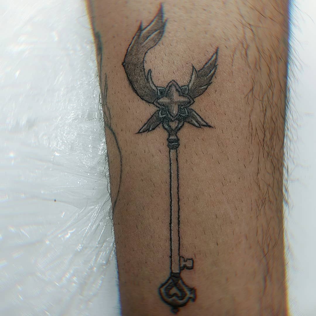 Small tattoo of Lux’s staff from League of Legends, with intricate details on the wings and star