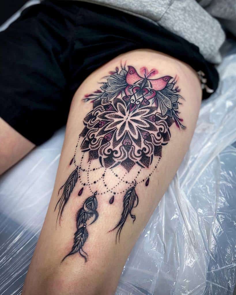 Thigh tattoo featuring an intricate butterfly design with feathers and a dreamcatcher motif