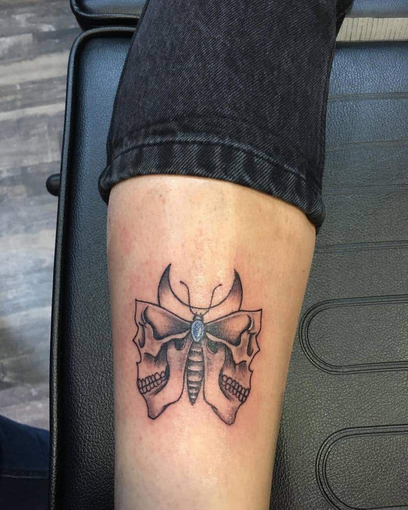Tattoo of a butterfly with skulls on its wings on a leg