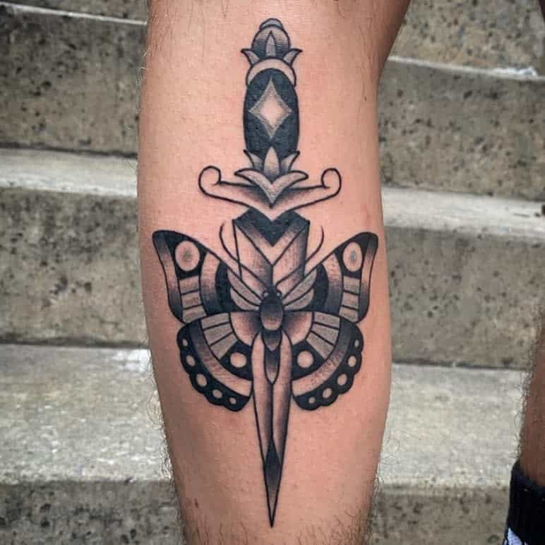 Tattoo of a dagger vertically piercing a butterfly on someone's leg