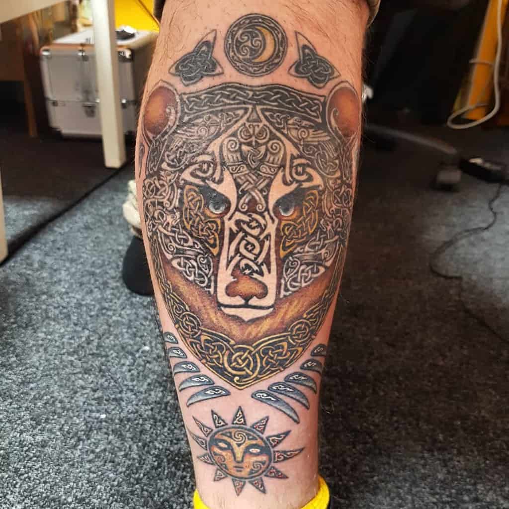 Intricate bear tattoo on leg with Celtic designs, sun, and moon elements