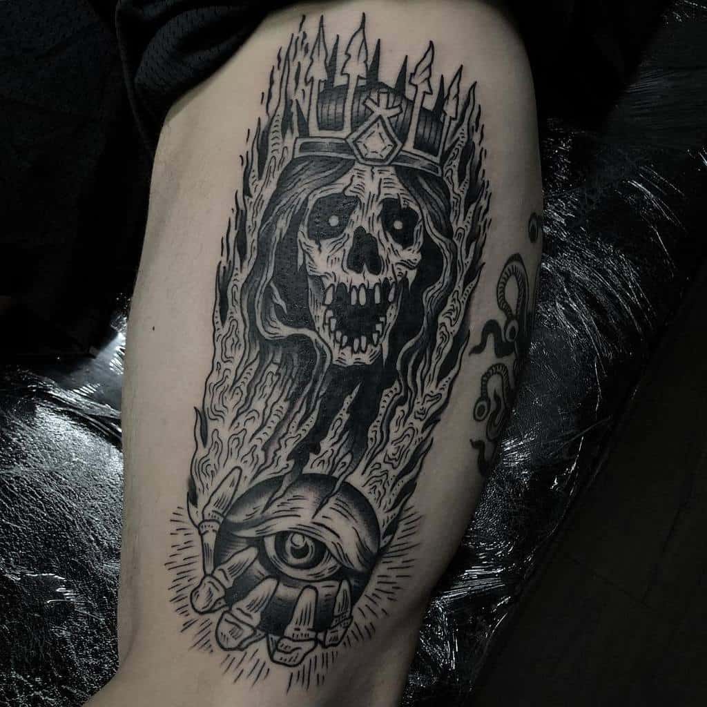 Dark, monochrome lich tattoo with a flaming skull crown and an ominous hand holding an eyeball