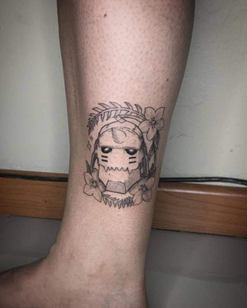 Fullmetal Alchemist tattoo of Alphonse Elric’s armored head, surrounded by delicate flowers and leaves in a fine-line minimalist style