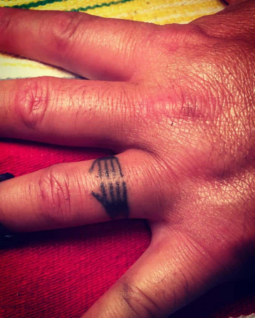 The ring tattoo features two hands gently wrapping around the finger