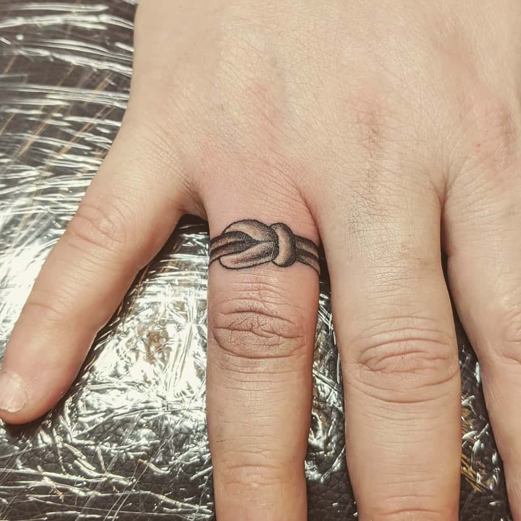A detailed black ink ring tattoo of a knot, in a loop, symbolizing connection or unity