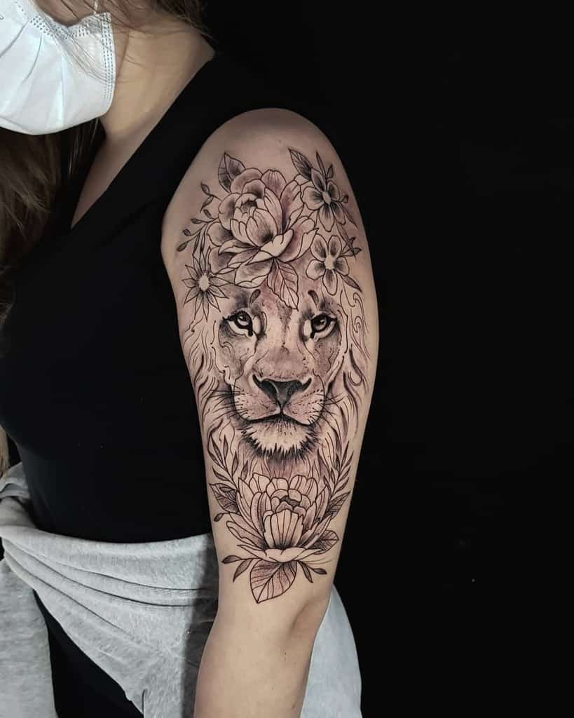 Tattoo of a lion with flowers on a woman's upper arm