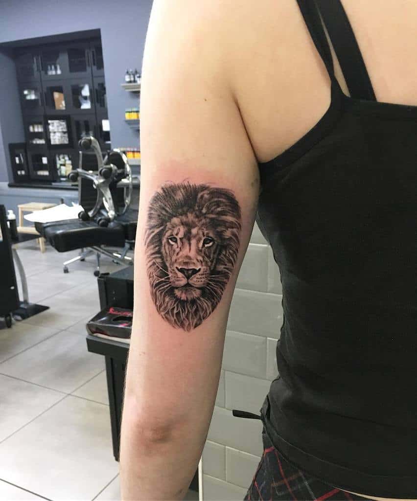 Realistic lion head tattoo on the upper arm