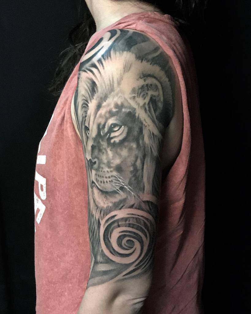 Arm tattoo of a lion's face and abstract swirls on a woman