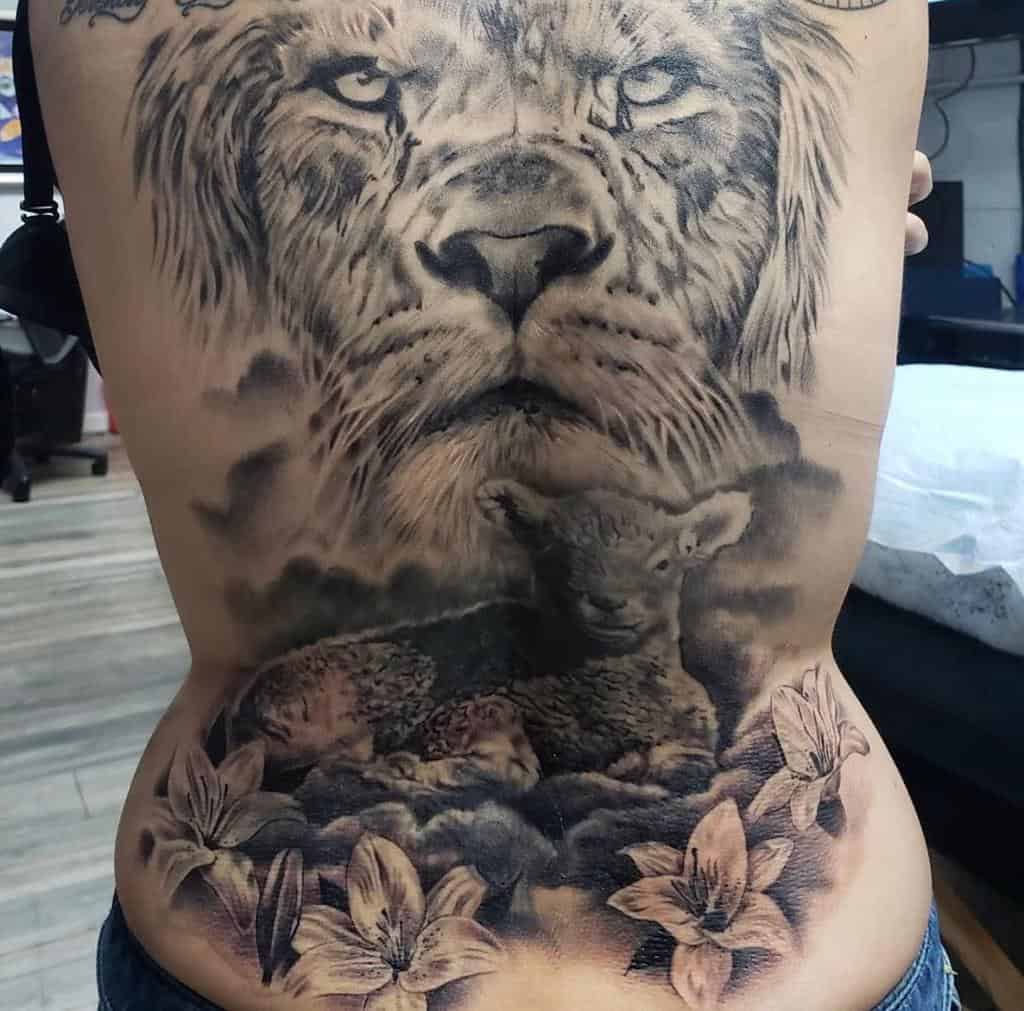 A detailed tattoo of a lion, lamb, and flowers seamlessly covering a person's back