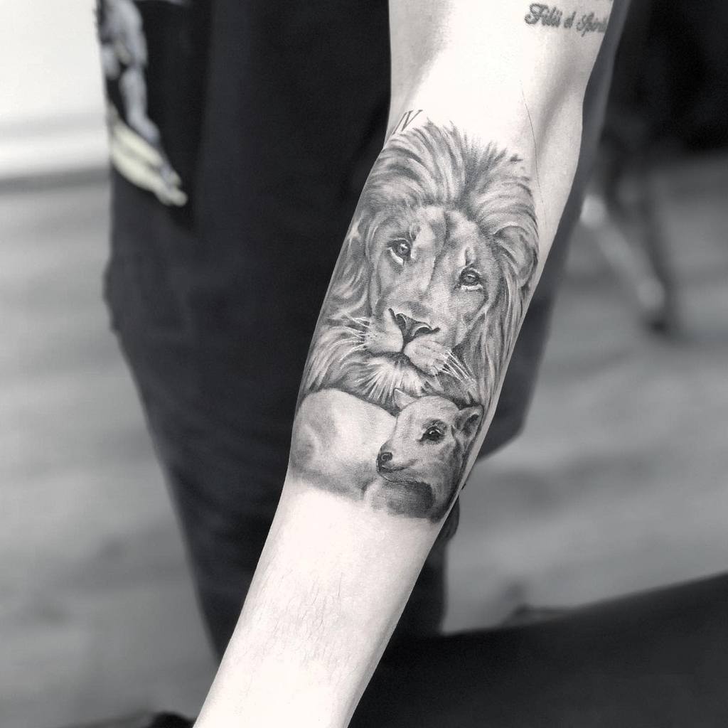 Forearm tattoo of a lion and a lamb intertwined in black and white