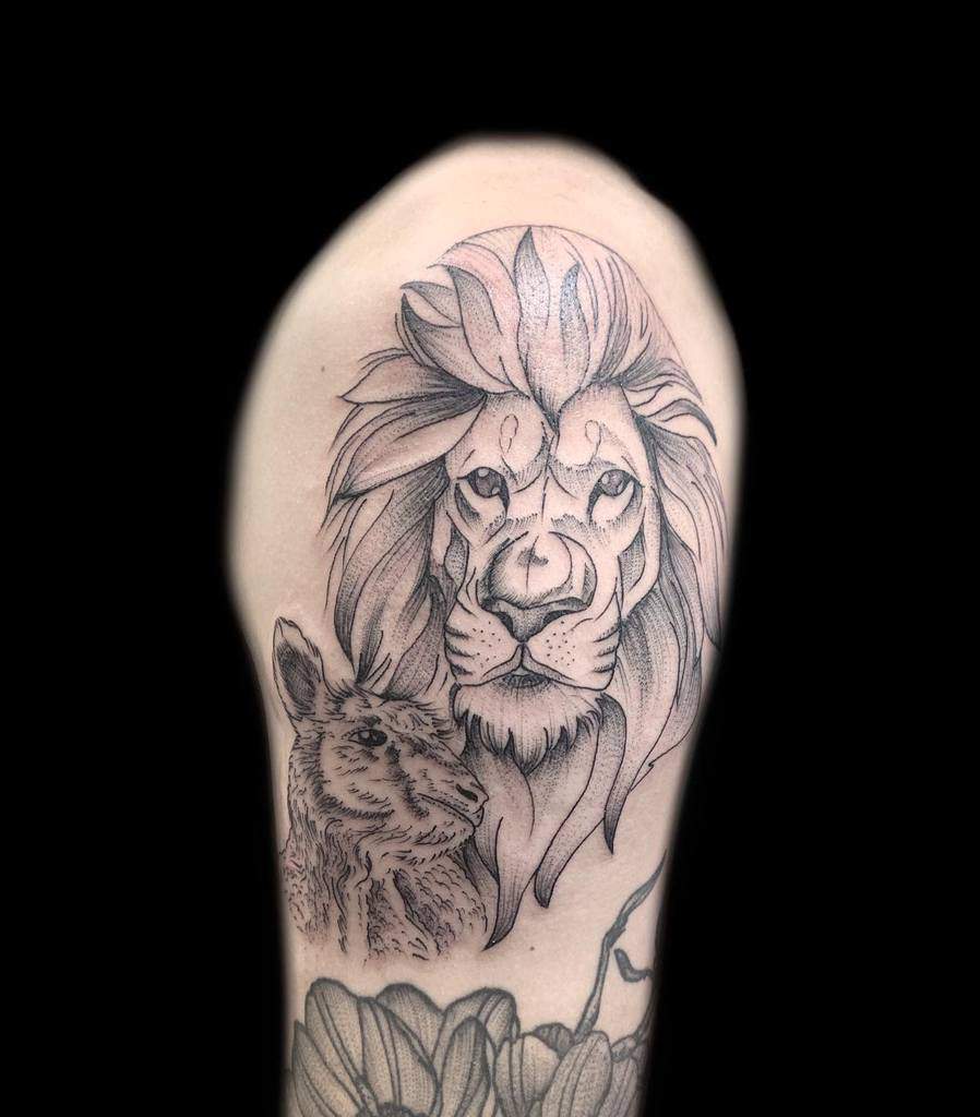 Tattoo of a lion's head and a kangaroo on an upper arm, with a floral design at the bottom, symbolizing strength and harmony