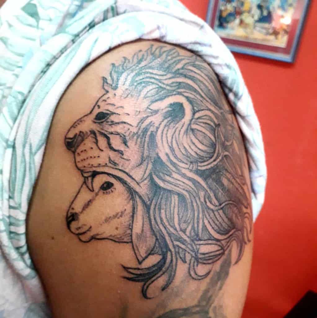 Tattoo of a lion and lamb intricately designed on an upper arm