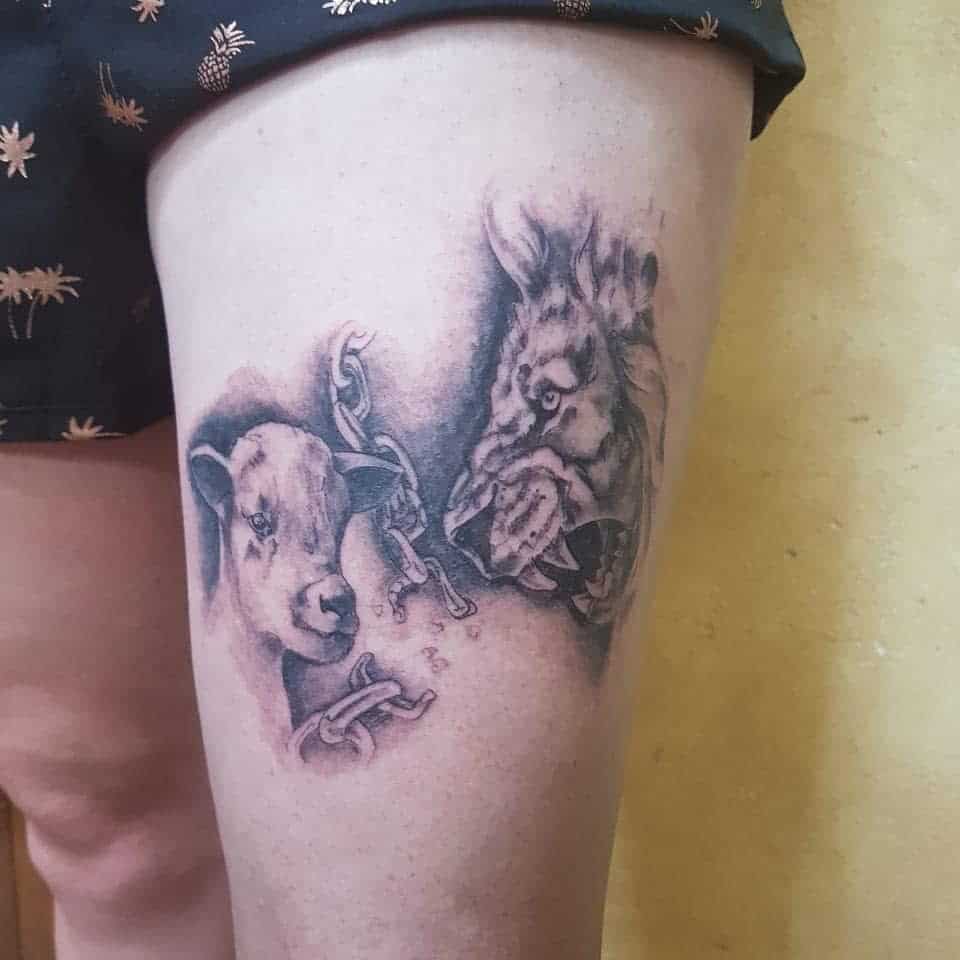 A tattoo of a chained goat's head, a lion, and a lamb on a person's thigh