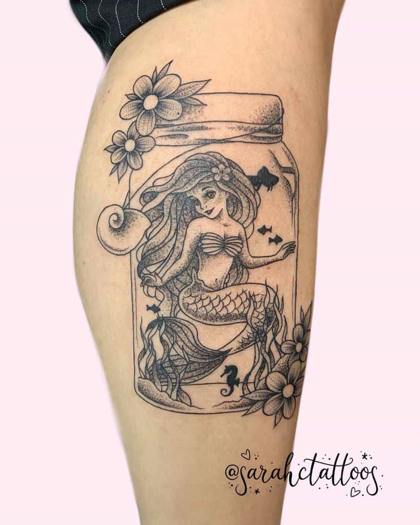 Unique black-and-white Ariel tattoo inside a mason jar design, surrounded by flowers, seaweed, and tiny fish for a whimsical look