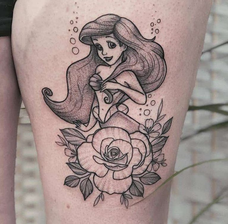 Charming black-and-gray tattoo of Ariel paired with a large blooming rose, surrounded by delicate bubbles and foliage on the thigh