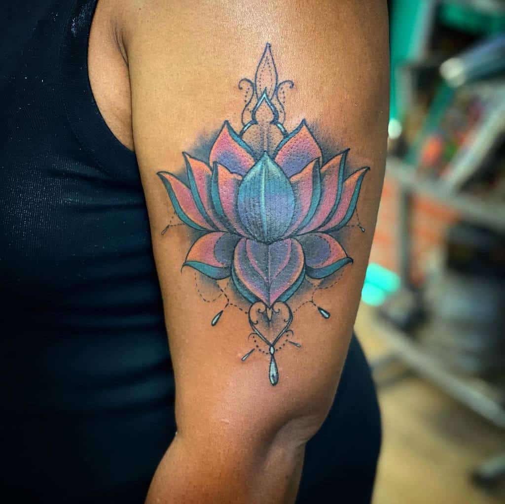 Colorful lotus flower tattoo on a person's upper arm with geometric and decorative elements