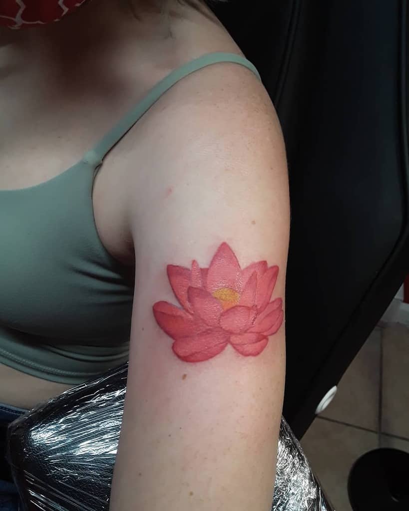 A pink lotus flower tattoo on a woman's upper arm